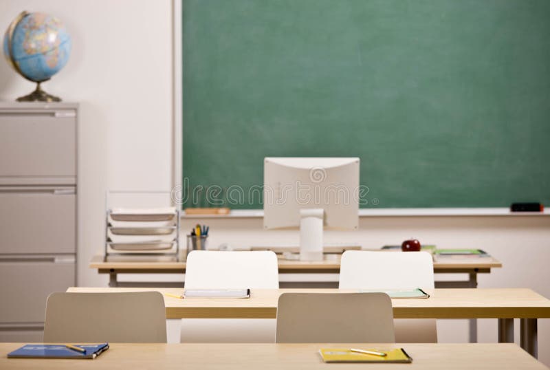Stoly, stoličky, tabuľu a počítač v prázdnej škole, triede.