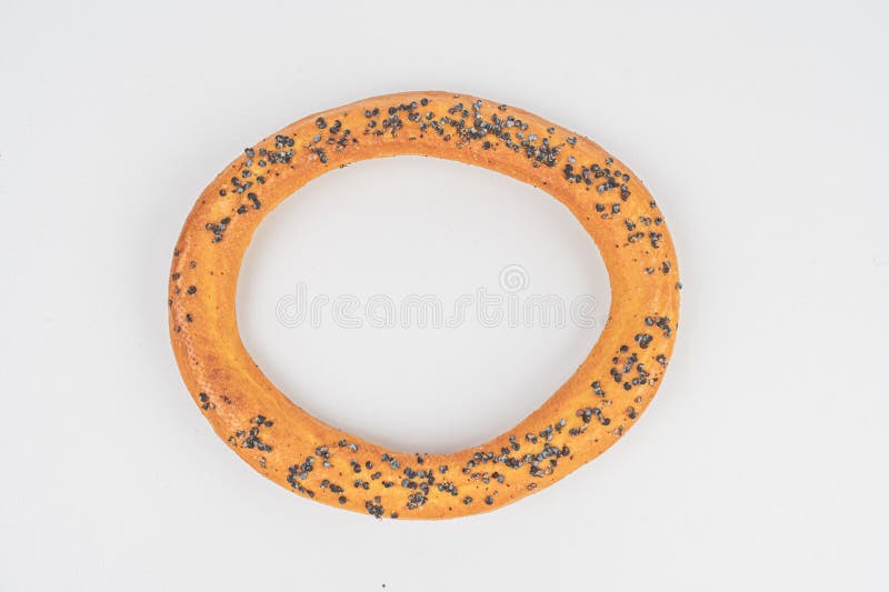 Image shows a circular donut with a hole forming another ring, possibly sesame seed-topped and presented against a plain royalty free stock photo