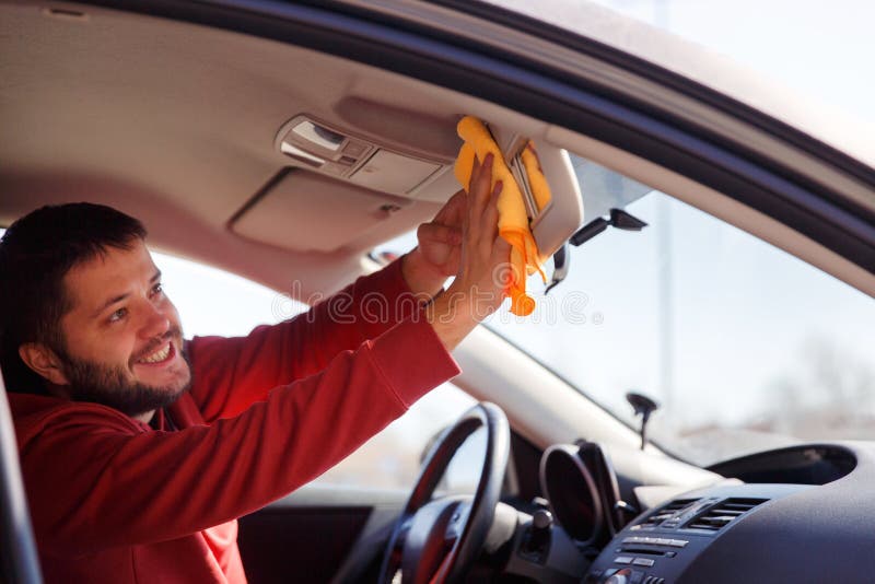 Image on side of happy male with orange rag washing mirror of car,close up