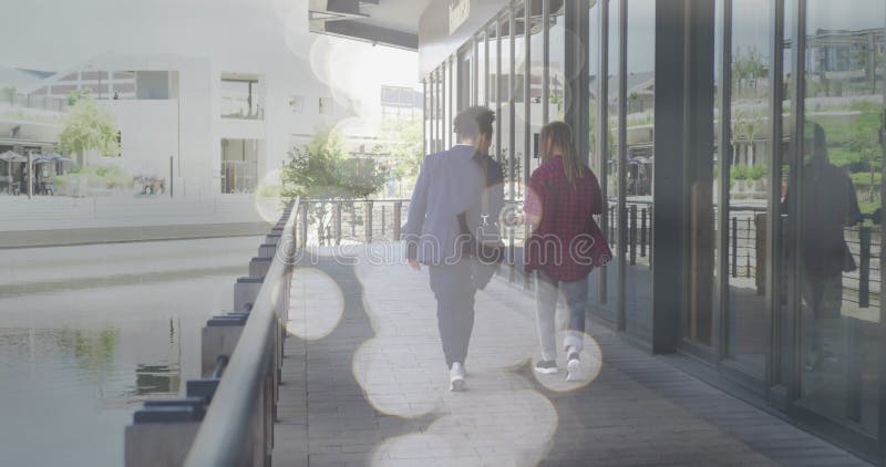 Image of spots of light over two smiling men walking in city stock photos