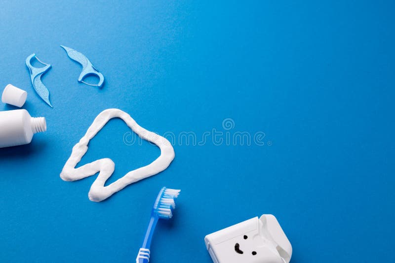 Image of toothbrush, toothpaste, string, liquid and tooth made of paste on blue surface stock images