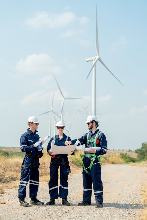 Image verticale d'un groupe de techniciens professionnels discutent du projet dans le plan papier et se tiennent devant. Image verticale d'un groupe de techniciens professionnels discutent du projet dans le plan papier et se tiennent en face de la éolienne ou de l'éolienne dans la zone d'activité de la centrale.
