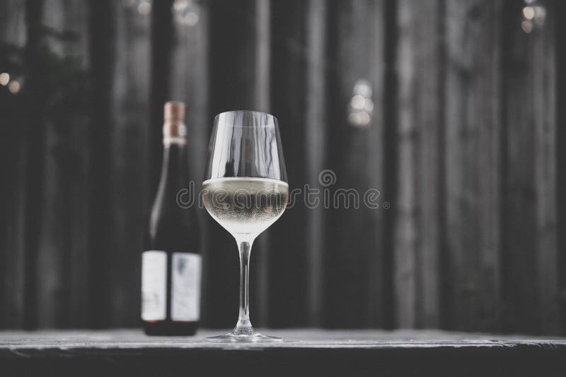 Image of White Wine Glass with White Wine Bottle and Blurry Background
