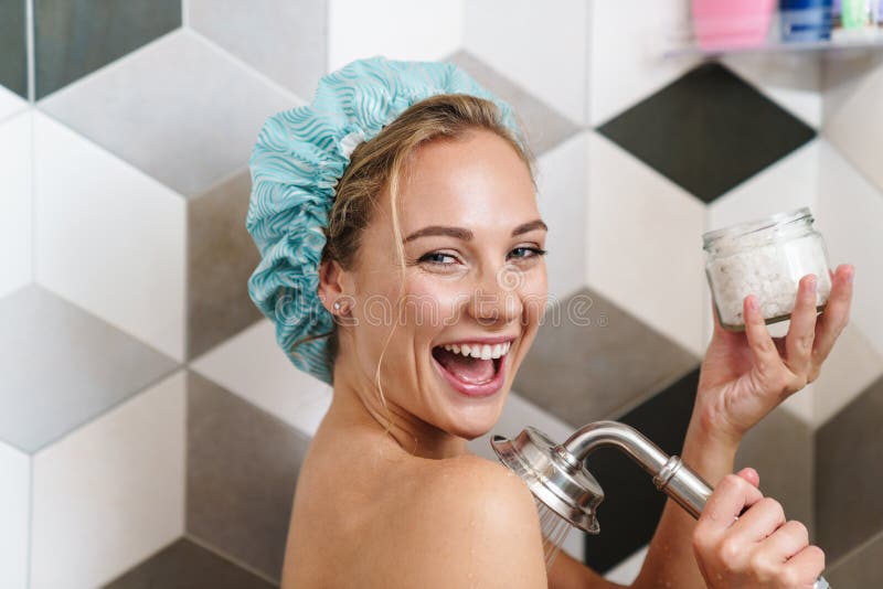 Image of young beautiful happy naked woman smiling while taking shower in bathroom at home. Image of young beautiful happy naked woman smiling while taking shower in bathroom at home