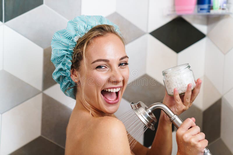 Image of young beautiful happy naked woman smiling while taking shower in bathroom at home. Image of young beautiful happy naked woman smiling while taking shower in bathroom at home