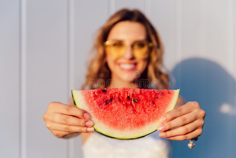 Imagem borrada da posição atrativa da menina com parte de melancia, fora foto de stock Imagem borrada da posição atrativa da menina com parte de melancia, fora foto de stock