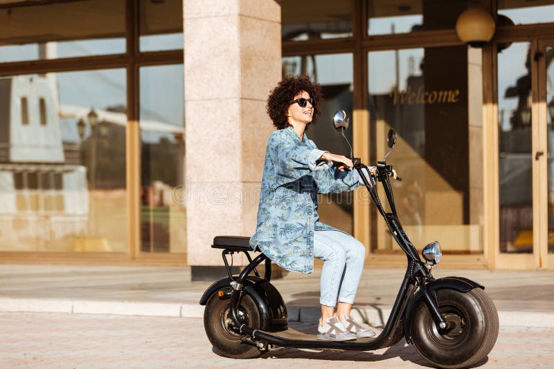 Imagem completa do comprimento da mulher encaracolado satisfeito nos óculos de sol fotos de stock