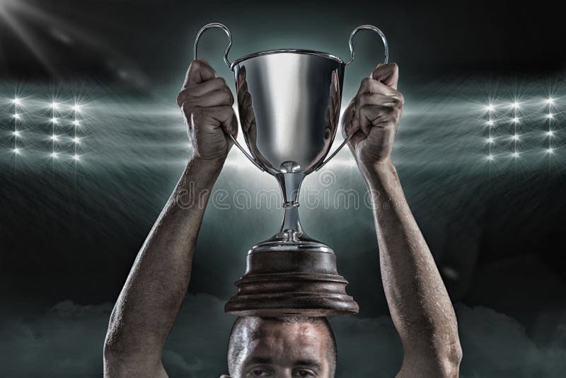 Imagem composta 3D do jogador bem sucedido do rugby que guarda o troféu imagem de stock Imagem composta 3D do jogador bem sucedido do rugby que guarda o troféu imagem de stock