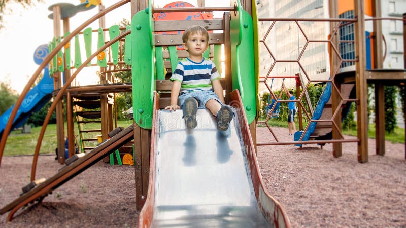 Imagem da equitação alegre de sorriso feliz e da escalada do menino da criança no campo de jogos grande das crianças no parque fotos de stock Imagem da equitação alegre de sorriso feliz e da escalada do menino da criança no campo de jogos grande das crianças no parque fotos de stock