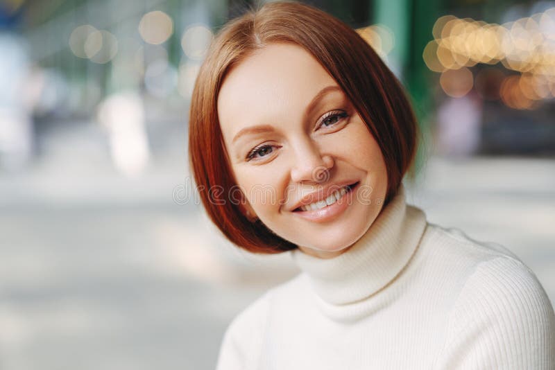 A imagem da jovem mulher atrativa com expressão contente, olha diretamente na câmera, satisfez o olhar, veste a camiseta da gola foto de stock A imagem da jovem mulher atrativa com expressão contente, olha diretamente na câmera, satisfez o olhar, veste a camiseta da gola foto de stock