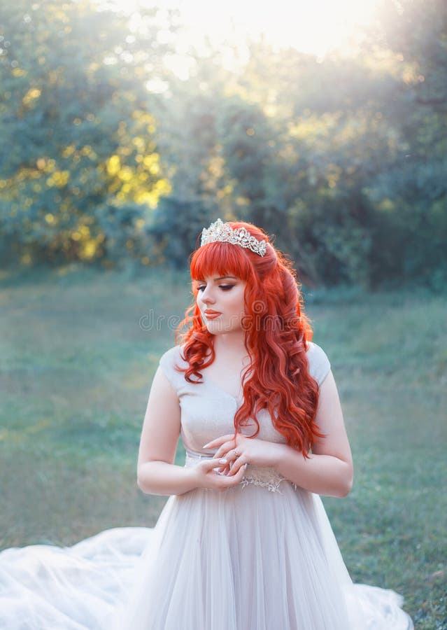 A imagem da rainha da floresta com cabelo ondulado vermelho brilhante, tiara e sorriso modesto, dobrou delicadamente seus mãos e fotos de stock A imagem da rainha da floresta com cabelo ondulado vermelho brilhante, tiara e sorriso modesto, dobrou delicadamente seus mãos e fotos de stock