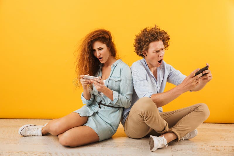 Imagem de pares entusiasmado ou de amigos homem e mulher que sentam-se no floo imagens de stock Imagem de pares entusiasmado ou de amigos homem e mulher que sentam-se no floo imagens de stock