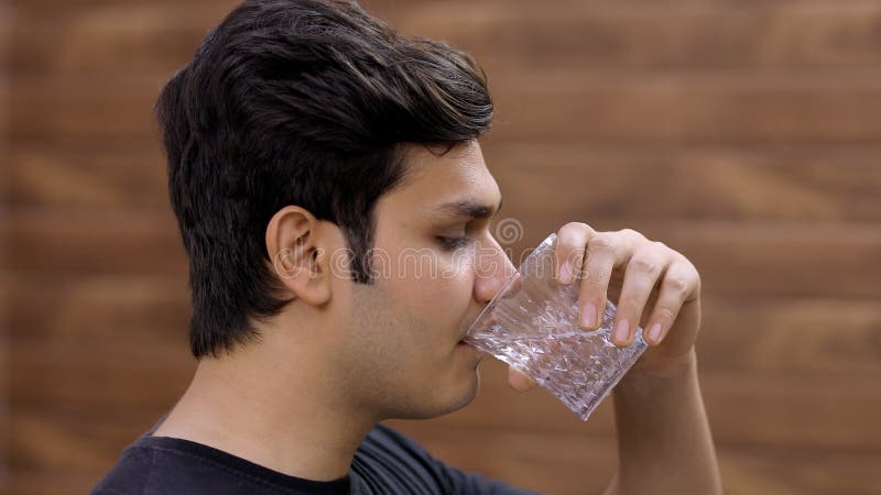 Imagem de um belo adolescente índio bebendo um copo cheio de água doce