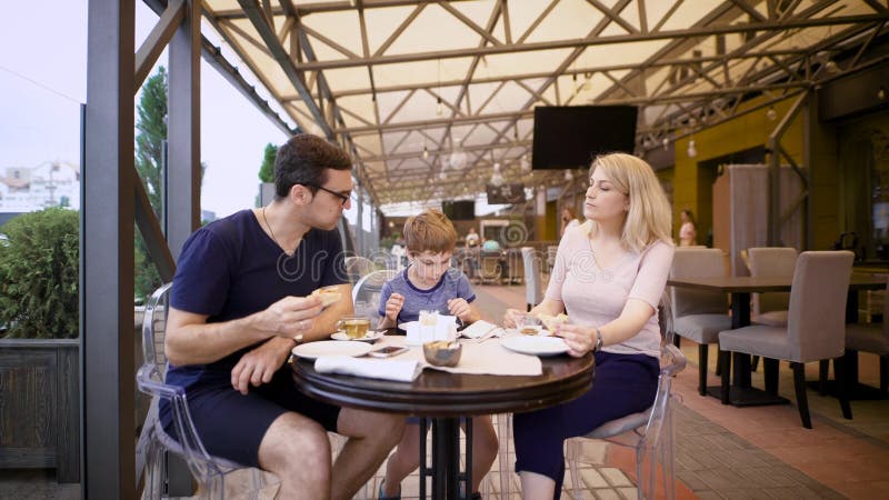 Imagem de uma família feliz e de seu filho no café Os pares loving com criança estão passando o tempo junto na pizaria