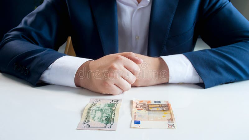 Imagem do close up do homem de negócios que duvida entre o investimento no euro ou o dinheiro do dólar fotos de stock royalty free Imagem do close up do homem de negócios que duvida entre o investimento no euro ou o dinheiro do dólar fotos de stock royalty free