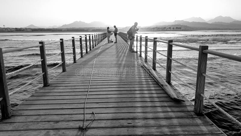 Imagen blanco y negro del embarcadero de madera largo en el oc? ano Ondas del mar tranquilo y puesta del sol que sorprende sobre l fotografía de archivo libre de regalías