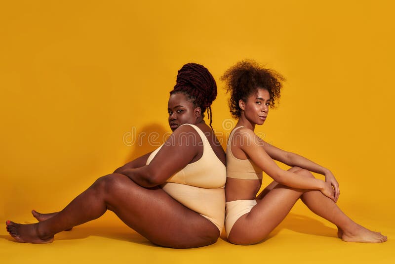 Imagen Completa De Dos Mujeres Afroamericanas En Ropa Interior Con  Diferente Tamaño Corporal Sentadas De Espaldas a Espaldas Foto de archivo -  Imagen de negro, aislado: 217400464