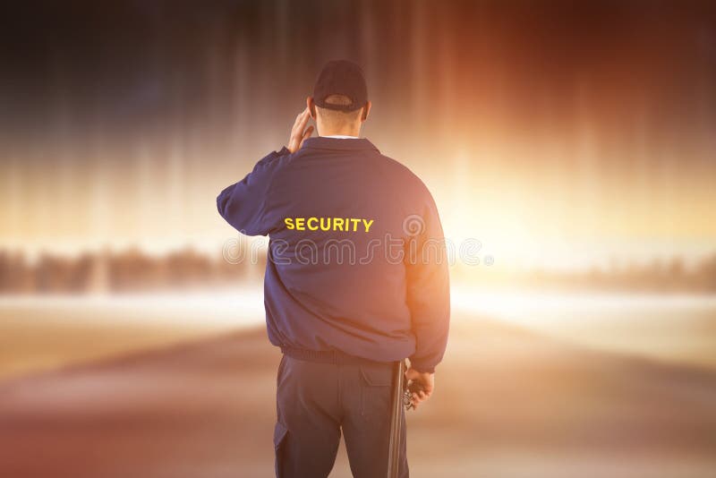 Imagen compuesta de la vista posterior del agente de seguridad que escucha el auricular fotografía de archivo Imagen compuesta de la vista posterior del agente de seguridad que escucha el auricular fotografía de archivo
