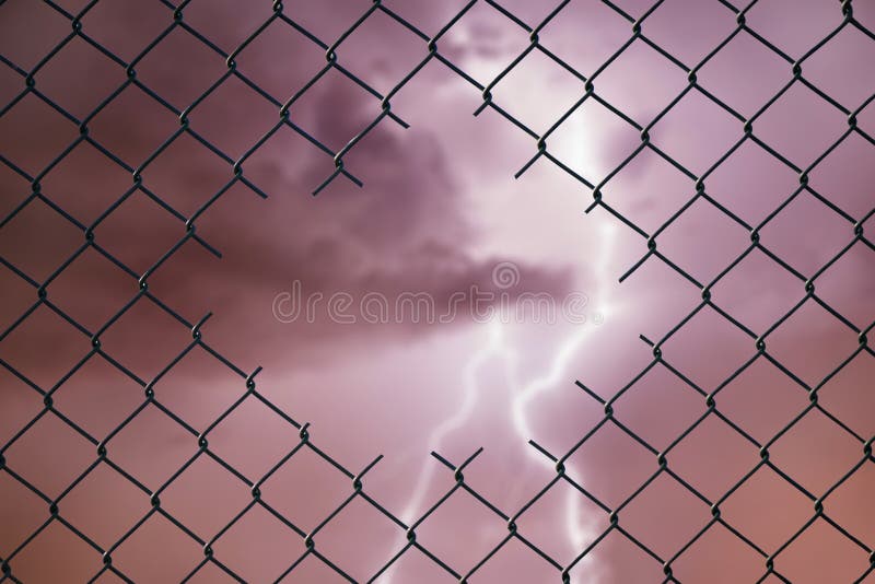 Imagen conceptual del relámpago en el cielo tempestuoso y la cerca de alambre de acero de la malla imagen de archivo Imagen conceptual del relámpago en el cielo tempestuoso y la cerca de alambre de acero de la malla imagen de archivo