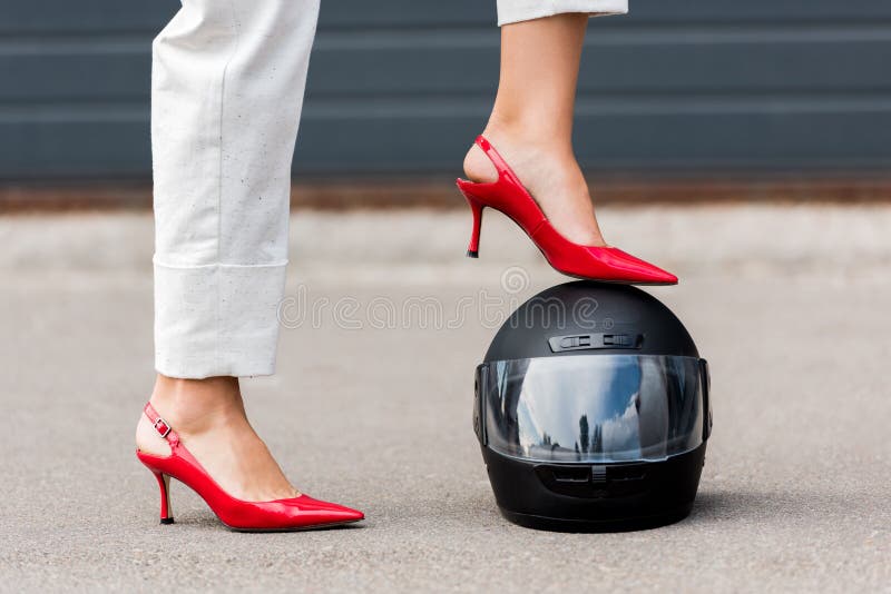 imagen cosechada de la mujer en los tacones altos rojos que ponen la pierna en casco de la motocicleta en la calle fotografía de archivo libre de regalías imagen cosechada de la mujer en los tacones altos rojos que ponen la pierna en casco de la motocicleta en la calle fotografía de archivo libre de regalías
