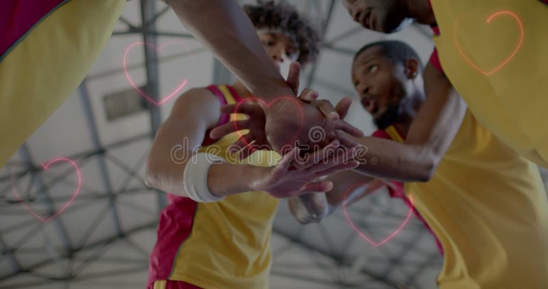 Imagen de corazones sobre diversos jugadores de baloncesto en la cancha imagen de archivo
