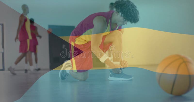 Imagen de la bandera de bahamas sobre diversos jugadores masculinos de baloncesto atando zapatos en el gimnasio foto de archivo libre de regalías