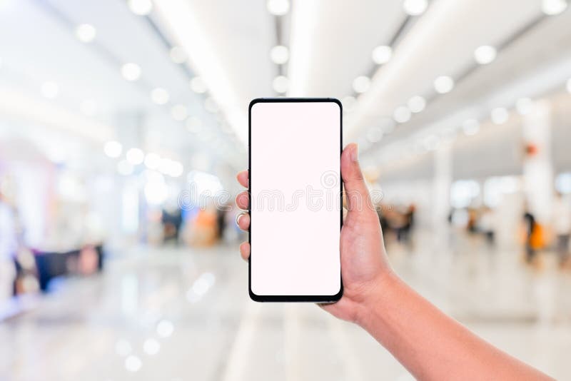 Imagen de la maqueta de la mano que sostiene el teléfono móvil con la pantalla blanca en blanco con la luz del bokeh del fondo de foto de archivo Imagen de la maqueta de la mano que sostiene el teléfono móvil con la pantalla blanca en blanco con la luz del bokeh del fondo de foto de archivo