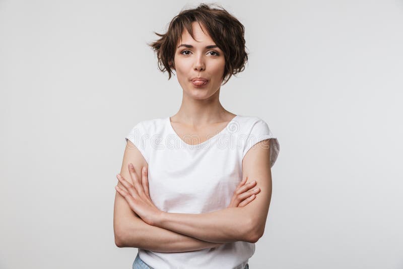 Imagen de la mujer linda en la camiseta básica que mira la cámara mientras que se coloca con los brazos cruzados foto de archivo libre de regalías Imagen de la mujer linda en la camiseta básica que mira la cámara mientras que se coloca con los brazos cruzados foto de archivo libre de regalías