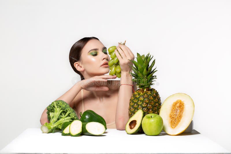Imagen de la mujer morena joven hermosa con las frutas y verduras en la tabla, sosteniendo las uvas verdes a disposici?n aisladas imagen de archivo Imagen de la mujer morena joven hermosa con las frutas y verduras en la tabla, sosteniendo las uvas verdes a disposici?n aisladas imagen de archivo