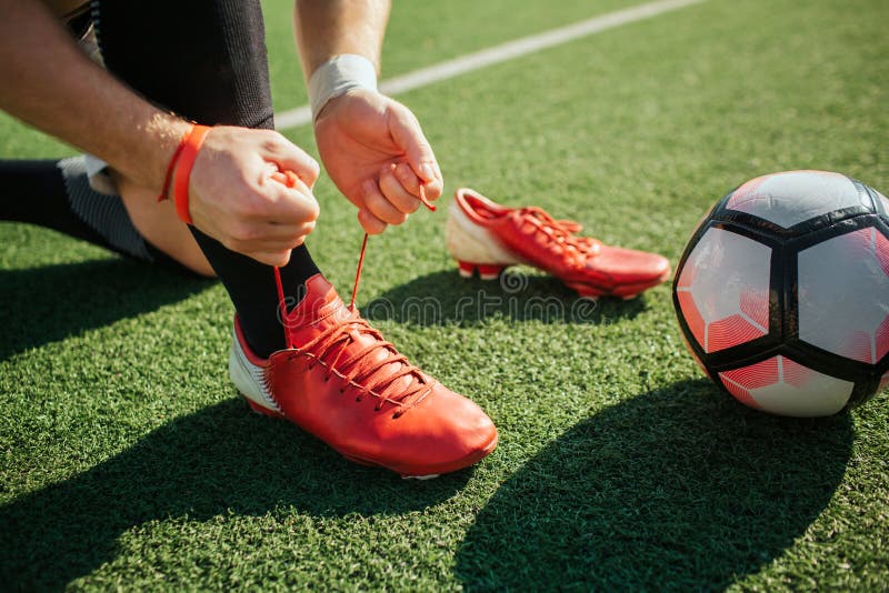 Imagen de la zapatilla de deporte del fútbol del cordón del hombre en una pierna Él se coloca en rodilla Otra zapatilla de deport fotografía de archivo Imagen de la zapatilla de deporte del fútbol del cordón del hombre en una pierna Él se coloca en rodilla Otra zapatilla de deport fotografía de archivo