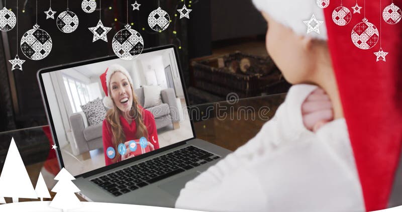 Imagen de nieve cayendo sobre una mujer sonriente en un sombrero de santa en una videollamada con su familia imagen de archivo