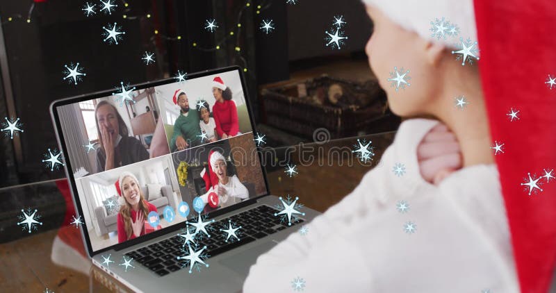 Imagen de nieve cayendo sobre una mujer sonriente en un sombrero de santa en una videollamada con su familia imagen de archivo libre de regalías