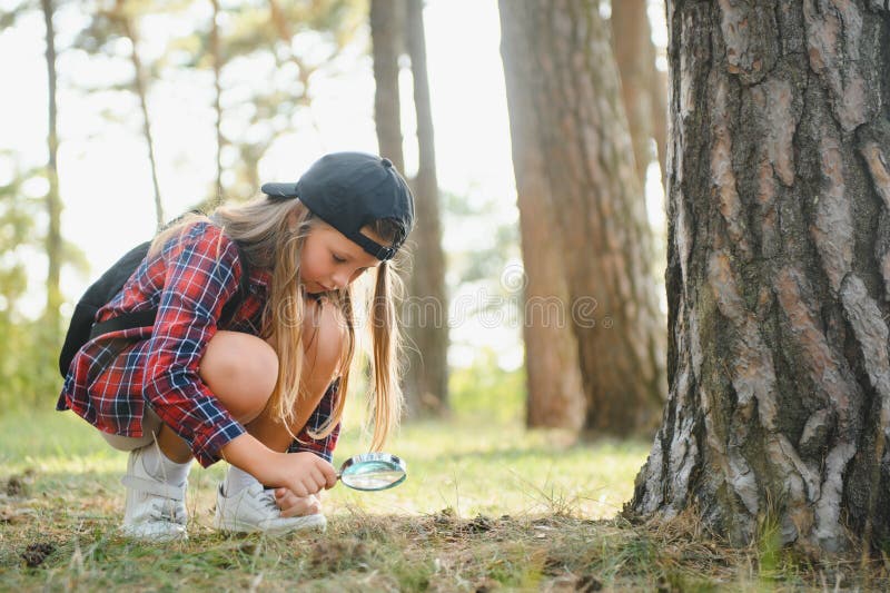 Imagen de un chico lindo con lupa explorando la naturaleza al aire libre. una niña adorable jugando en el bosque con. niña adorable jugando en el bosque con lupa. niño curioso mirando a través de la lupa en un día soleado en el parque.