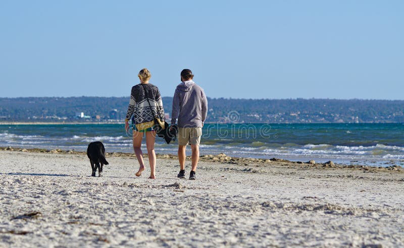Imagen de un par con su perro que camina en la playa imagen de archivo libre de regalías Imagen de un par con su perro que camina en la playa imagen de archivo libre de regalías