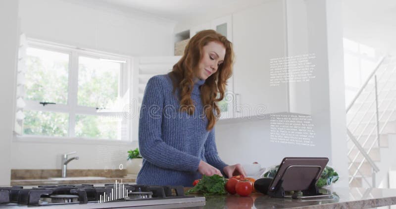 Imagen de una mujer preparando verduras frescas en una cocina moderna mientras utiliza una tableta digital foto de archivo libre de regalías