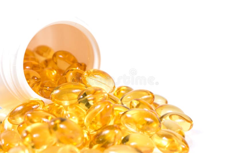 Selective focus image. Fish oil nutritional supplement capsules spilling out of a white pill bottle. Selective focus image. Fish oil nutritional supplement capsules spilling out of a white pill bottle.