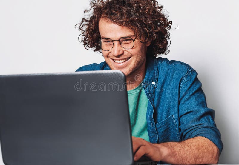 Imagen del hombre de negocios feliz joven con el pelo rizado que trabaja en su ordenador portátil en oficina Hombre sonriente ale imágenes de archivo libres de regalías Imagen del hombre de negocios feliz joven con el pelo rizado que trabaja en su ordenador portátil en oficina Hombre sonriente ale imágenes de archivo libres de regalías