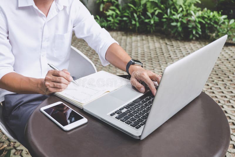 Imagen del hombre de negocios que trabaja con el ordenador port?til y los datos financieros sobre la tabla en oficina al aire lib fotografía de archivo Imagen del hombre de negocios que trabaja con el ordenador port?til y los datos financieros sobre la tabla en oficina al aire lib fotografía de archivo