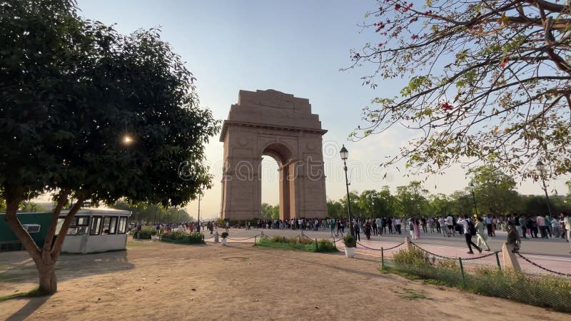 Imagen en ángulo bajo del monumento The India Gate con una multitud al atardecer almacen de video