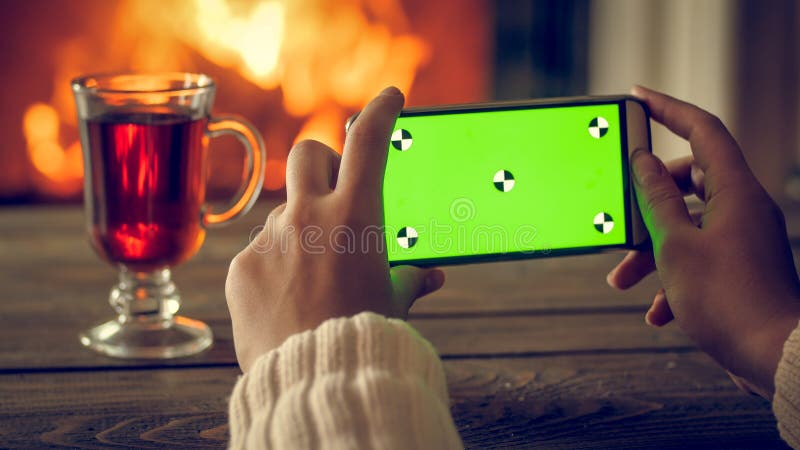 Imagen entonada del primer de las manos femeninas que hacen la foto en el smartphone del té y de la chimenea ardiente en la noche imágenes de archivo libres de regalías Imagen entonada del primer de las manos femeninas que hacen la foto en el smartphone del té y de la chimenea ardiente en la noche imágenes de archivo libres de regalías