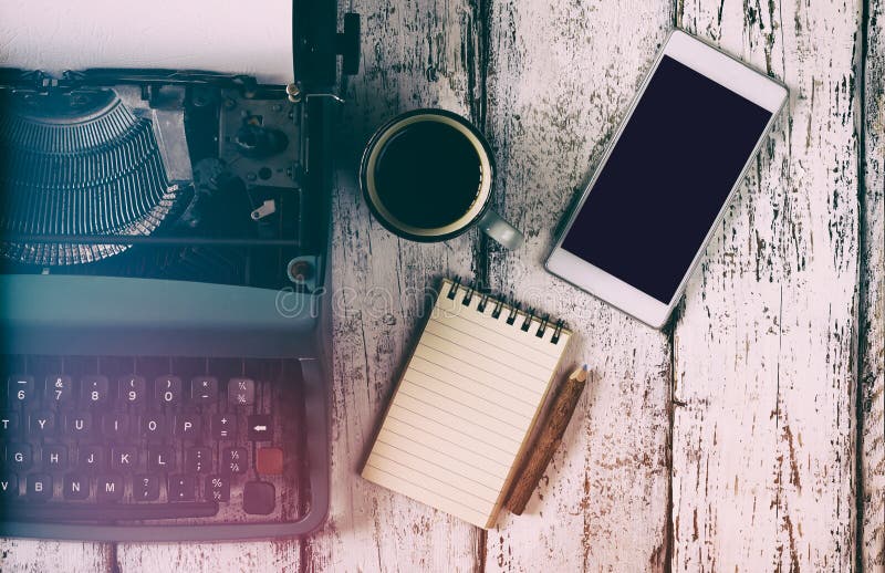 Imagen filtrada retra de la máquina de escribir del vintage, del cuaderno en blanco, de la taza de café y del smartphone en la ta imágenes de archivo libres de regalías Imagen filtrada retra de la máquina de escribir del vintage, del cuaderno en blanco, de la taza de café y del smartphone en la ta imágenes de archivo libres de regalías