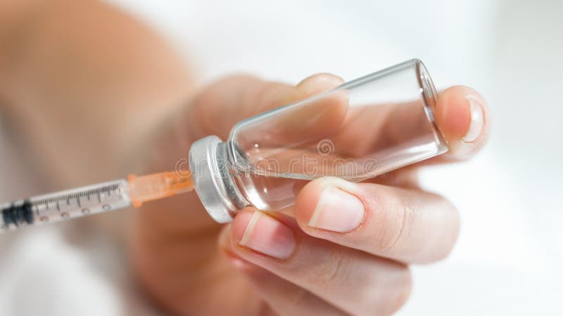 Imagen macra de las manos femeninas que sostienen pequeña ampolla de la jeringuilla y del vidrio con la medicación foto de archivo Imagen macra de las manos femeninas que sostienen pequeña ampolla de la jeringuilla y del vidrio con la medicación foto de archivo
