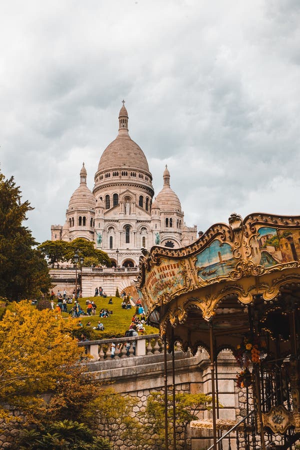 Imagen vertical de La BasÃlica del Sagrado Corazón de ParÃs o Sacre Coeur cerca de un carrusel en Francia imágenes de archivo libres de regalías Imagen vertical de La BasÃlica del Sagrado Corazón de ParÃs o Sacre Coeur cerca de un carrusel en Francia imágenes de archivo libres de regalías