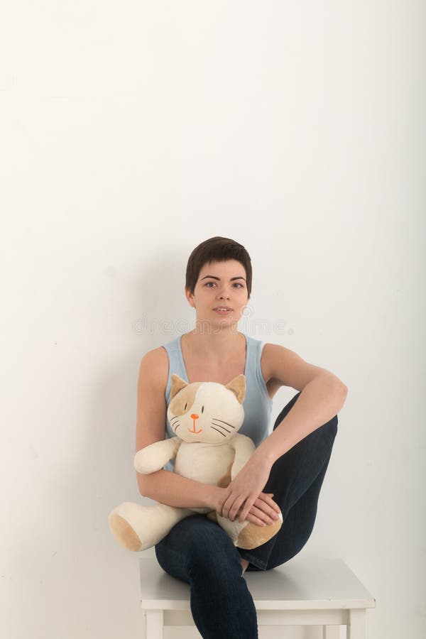 Imagen vertical de la chica joven que mira la cámara, retrato de una mujer morena hermosa con un gato precioso del juguete de la imágenes de archivo libres de regalías Imagen vertical de la chica joven que mira la cámara, retrato de una mujer morena hermosa con un gato precioso del juguete de la imágenes de archivo libres de regalías