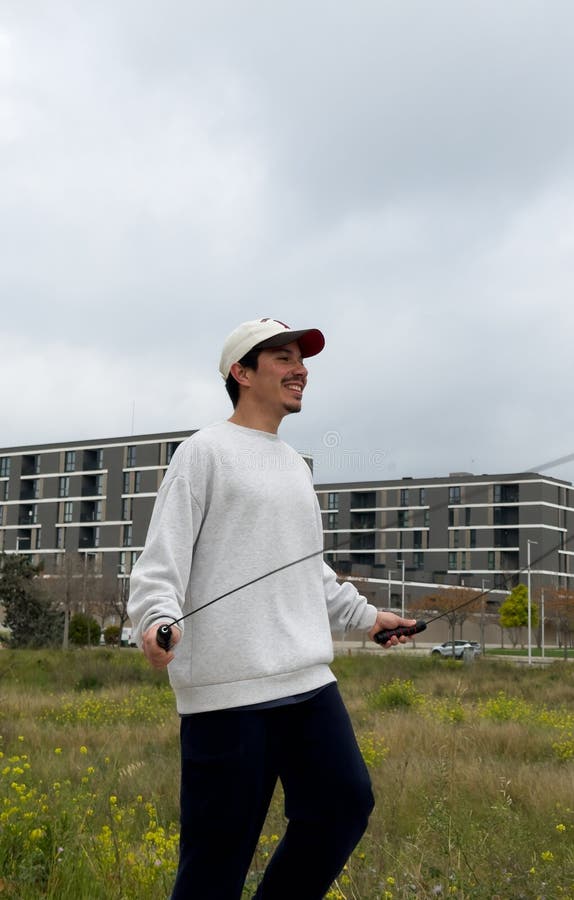 Imagen vertical de un joven saltando una cuerda al aire libre en un día nublado fotos de archivo libres de regalías