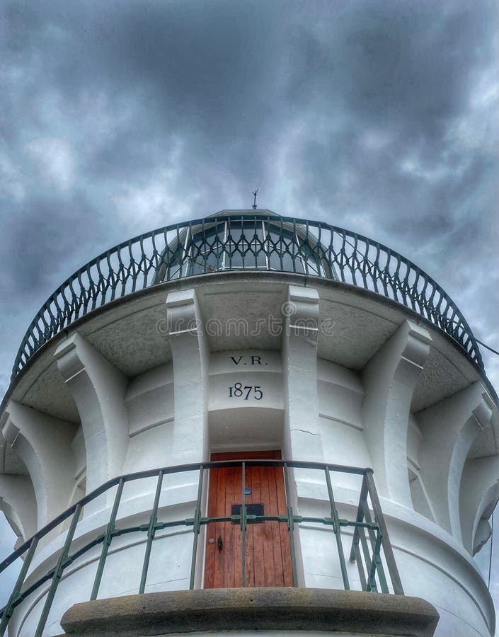 Imagen vertical de ángulo bajo de una torre blanca con una puerta marrón en un día nublado foto de archivo