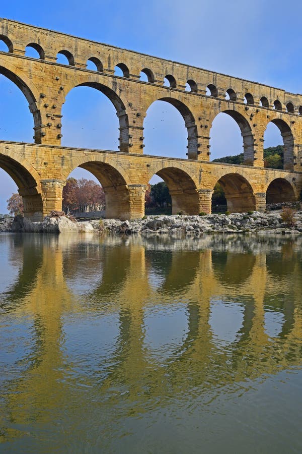 Imagen vertical del nivel de tres arcos de Pont du Gard con la reflexión clara en el río de Gardon Imagen vertical del nivel de tres arcos de Pont du Gard con la reflexión clara en el río de Gardon
