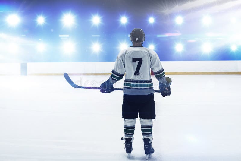 Immagine composita del giocatore di hockey con la condizione del bastone di hockey sulla pista di pattinaggio fotografie stock Immagine composita del giocatore di hockey con la condizione del bastone di hockey sulla pista di pattinaggio fotografie stock