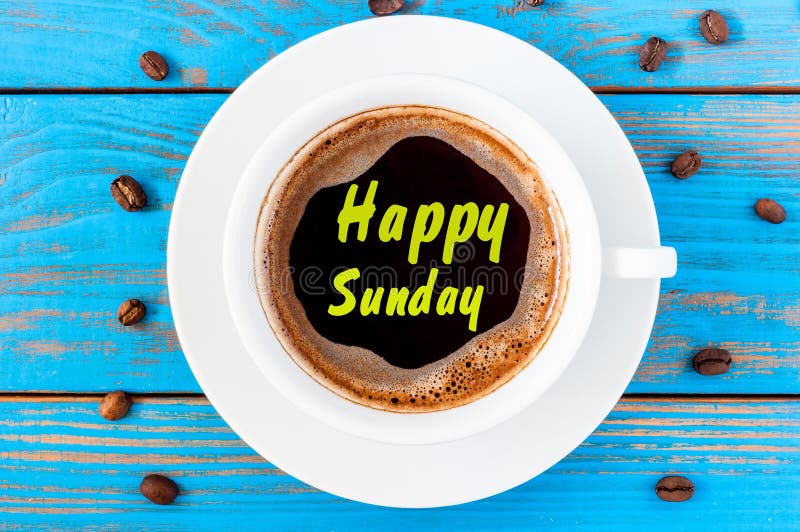 Top view image of morning coffee cup with phrase: happy sunday on blue wooden background. Weekend breakfast concept. Top view image of morning coffee cup with phrase: happy sunday on blue wooden background. Weekend breakfast concept.