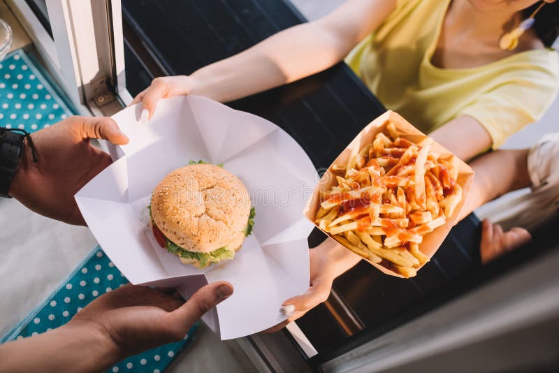 immagine potata del cuoco unico che dà hamburger e le patate fritte ai clienti dal camion dell'alimento immagini stock libere da diritti immagine potata del cuoco unico che dà hamburger e le patate fritte ai clienti dal camion dell'alimento immagini stock libere da diritti